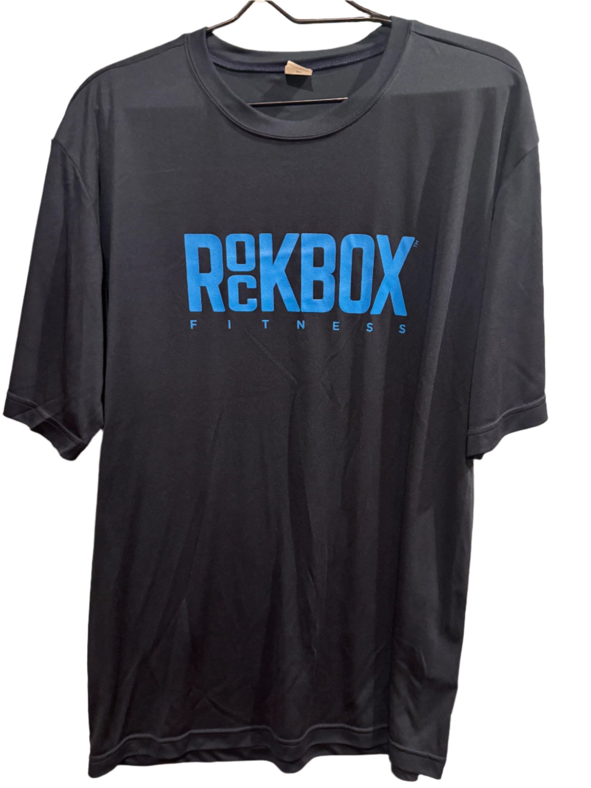 Black sleeveless shirt with blue 'ROCKBOX FITNESS' text on a beige surface