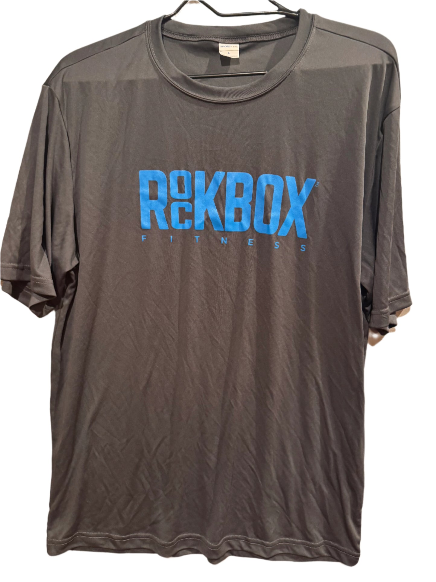 Gray t-shirt with blue 'ROCKBOX' logo on a beige surface