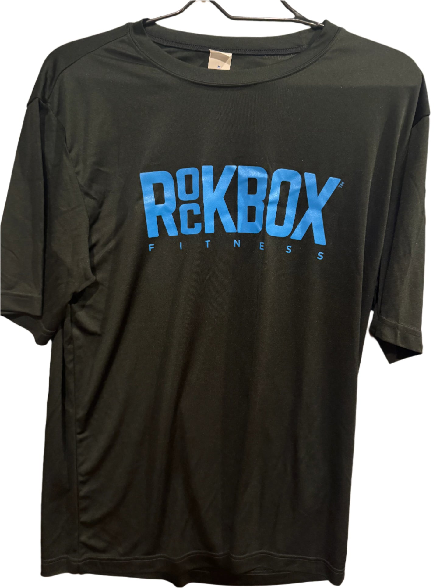 Black t-shirt with blue 'ROCKBOX' branding on a beige surface