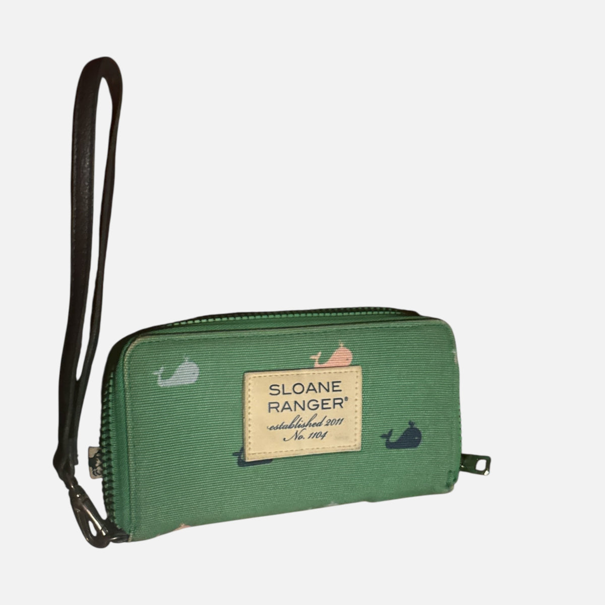 The Xchange Sloane Ranger green denim wallet with a navy and coral whale print, zip closure, and wrist strap.