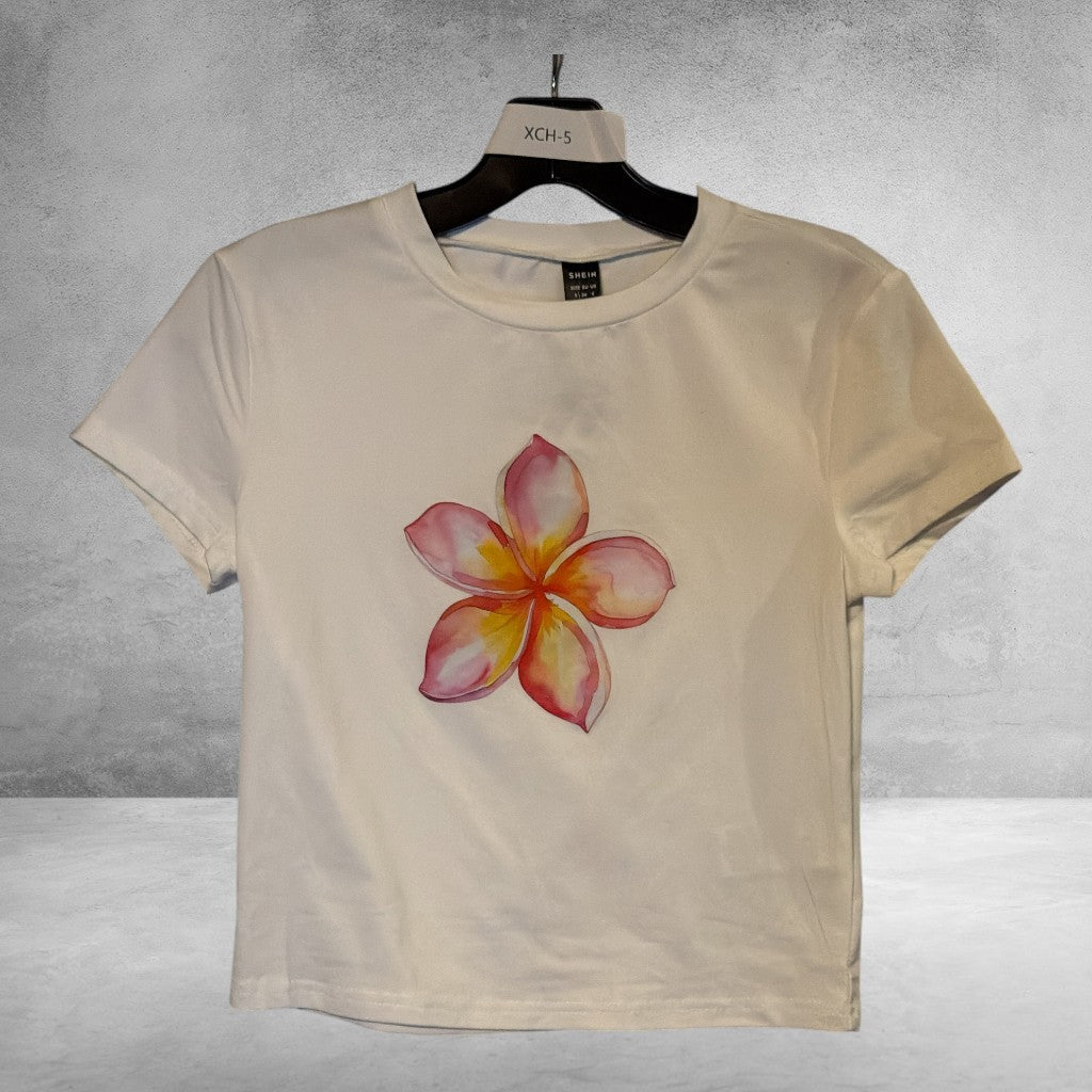 The Xchange white short sleeve crew neck t-shirt featuring a vibrant watercolor plumeria flower graphic print.